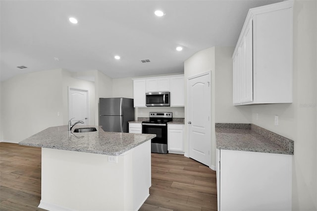 kitchen with appliances with stainless steel finishes, light hardwood / wood-style flooring, white cabinets, sink, and a kitchen island with sink