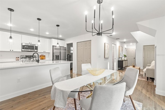 dining room with light wood-type flooring, sink, and a chandelier