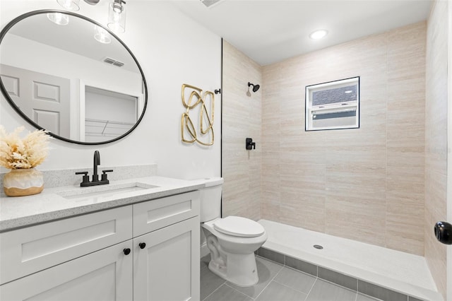 bathroom featuring a tile shower, tile patterned flooring, vanity, and toilet