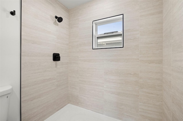 bathroom featuring a tile shower and toilet