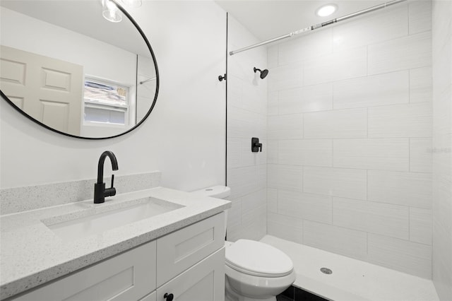 bathroom with vanity, toilet, and tiled shower