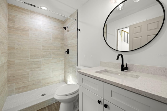 bathroom with tiled shower, vanity, hardwood / wood-style flooring, and toilet