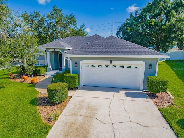 ranch-style house featuring concrete driveway, roof with shingles, a front yard, stucco siding, and an attached garage