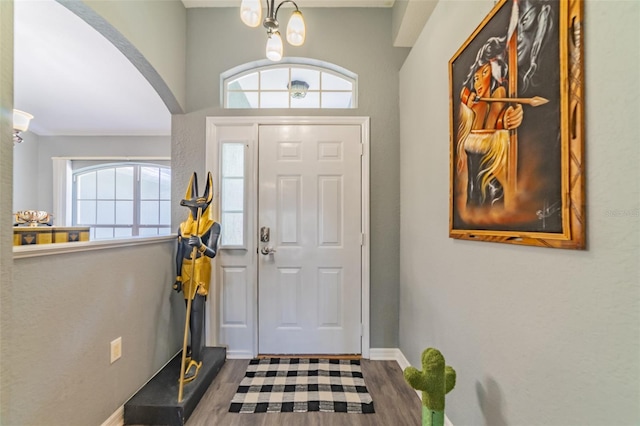 foyer featuring arched walkways, baseboards, and wood finished floors