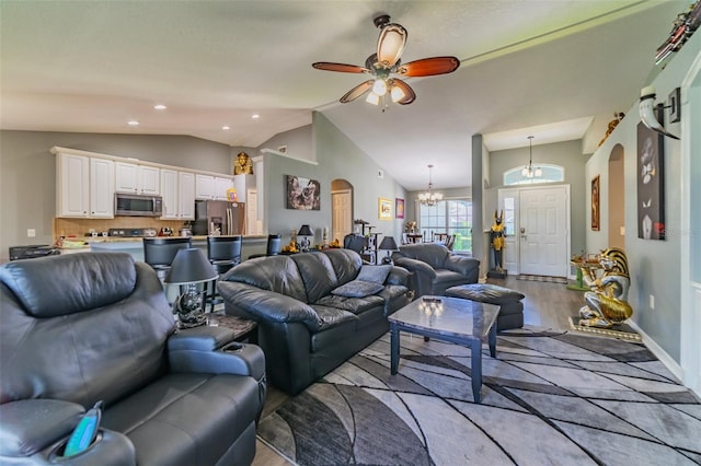 living room with arched walkways, ceiling fan with notable chandelier, lofted ceiling, and wood finished floors