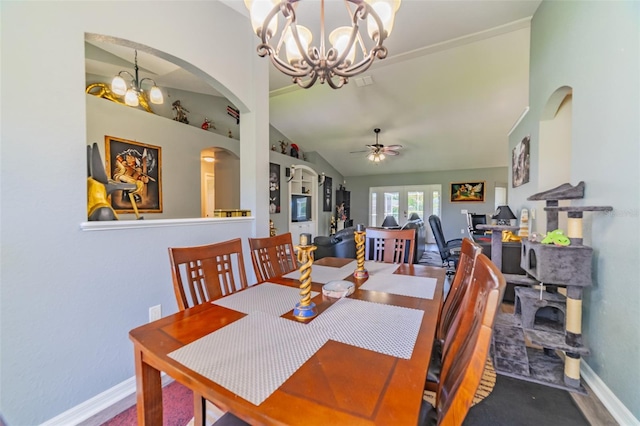 dining room with visible vents, baseboards, lofted ceiling, ceiling fan with notable chandelier, and arched walkways