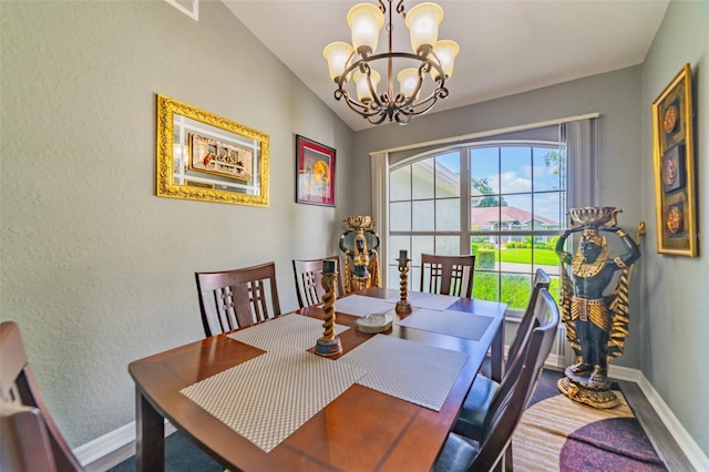 dining area featuring an inviting chandelier, vaulted ceiling, wood finished floors, and baseboards