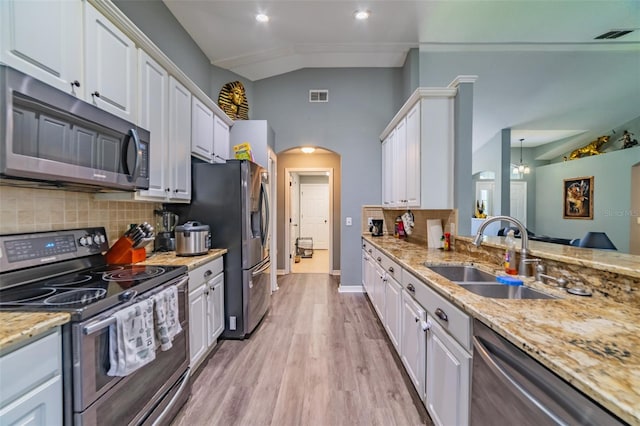 kitchen featuring a sink, arched walkways, appliances with stainless steel finishes, and white cabinetry