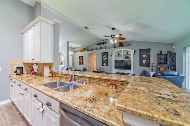 kitchen featuring light stone countertops, arched walkways, a sink, white cabinets, and open floor plan