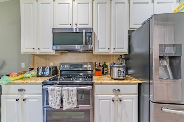 kitchen featuring light stone countertops, tasteful backsplash, appliances with stainless steel finishes, and white cabinetry