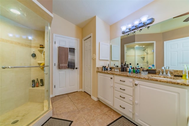 full bathroom featuring a sink, a stall shower, double vanity, and tile patterned flooring