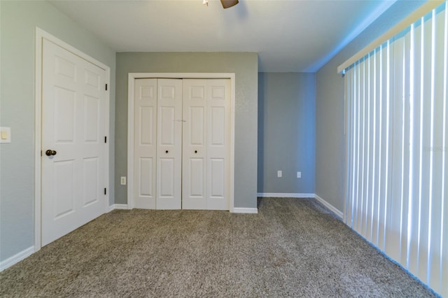 unfurnished bedroom with a closet, baseboards, carpet, and a ceiling fan