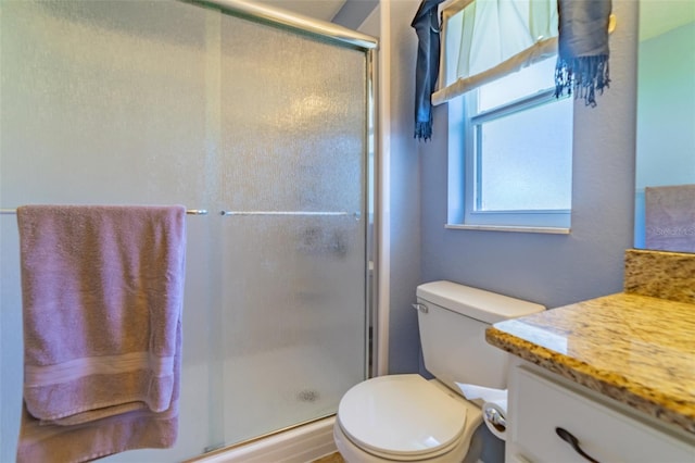 bathroom with vanity, a shower stall, and toilet