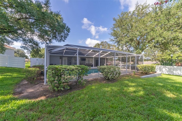 back of house with glass enclosure, an outdoor pool, a lawn, and fence