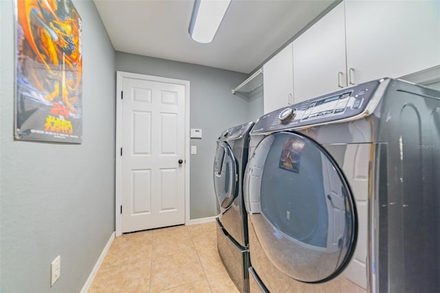 clothes washing area with cabinet space, light tile patterned flooring, separate washer and dryer, and baseboards