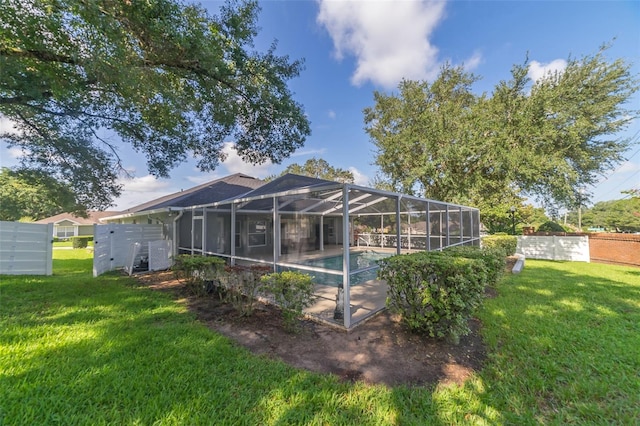 back of property featuring a lanai, an outdoor pool, a yard, and fence