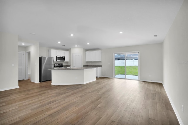 kitchen featuring a center island with sink, white cabinetry, appliances with stainless steel finishes, and light wood-type flooring