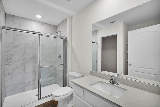 bathroom with hardwood / wood-style floors, vanity, walk in shower, and toilet