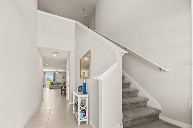 stairs featuring light tile patterned floors and a high ceiling