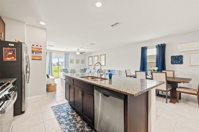 kitchen with light tile patterned floors, a kitchen island with sink, ceiling fan, stainless steel appliances, and sink