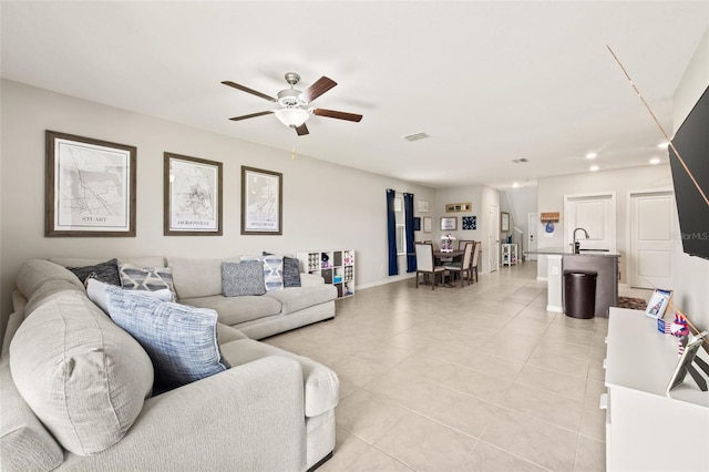 living room featuring light tile patterned flooring, sink, and ceiling fan