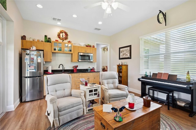 living area featuring baseboards, a ceiling fan, visible vents, and light wood-type flooring
