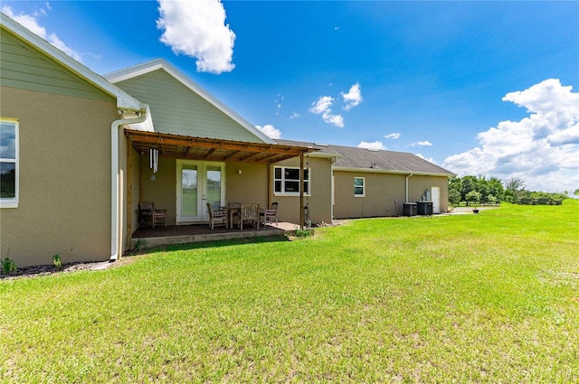 back of house featuring stucco siding, central air condition unit, a patio, and a lawn