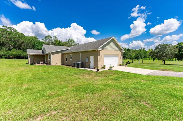 view of side of property with central AC, a garage, and a lawn