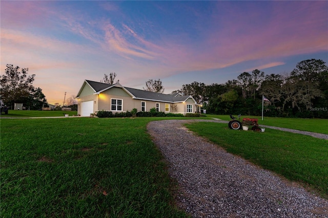 ranch-style home featuring a garage and a yard