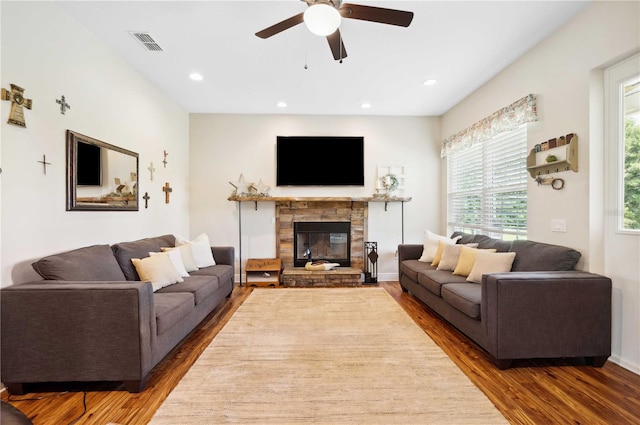 living room featuring dark hardwood / wood-style flooring, ceiling fan, and a fireplace