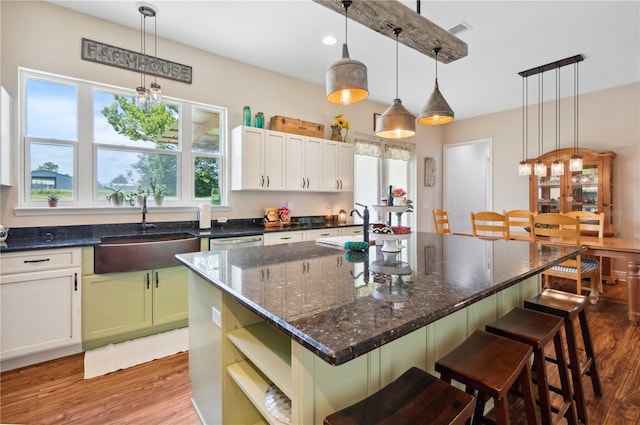 kitchen with sink, a breakfast bar area, hanging light fixtures, light hardwood / wood-style flooring, and a kitchen island