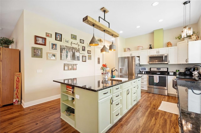 kitchen featuring stainless steel appliances, sink, decorative light fixtures, wood-type flooring, and a center island