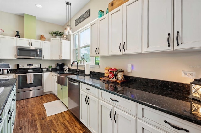 kitchen featuring stainless steel appliances, dark hardwood / wood-style flooring, white cabinets, sink, and decorative light fixtures