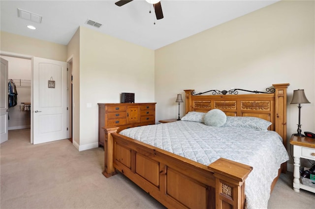 bedroom with light colored carpet, ceiling fan, a walk in closet, and a closet