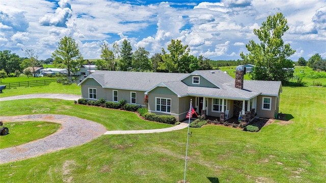 ranch-style home featuring a porch, a chimney, fence, curved driveway, and a front yard