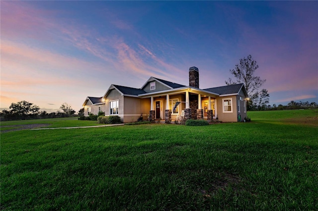view of front of property featuring a porch, a lawn, and a chimney