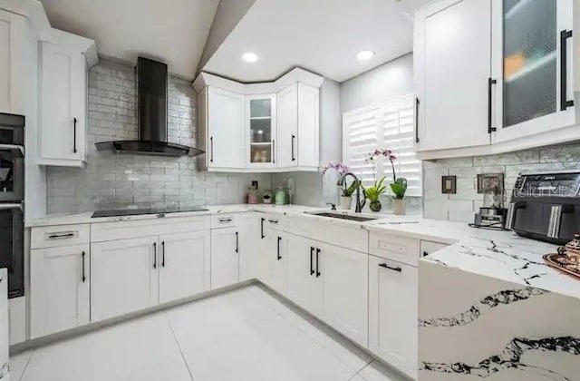 kitchen with decorative backsplash, white cabinetry, wall chimney exhaust hood, and light tile patterned floors