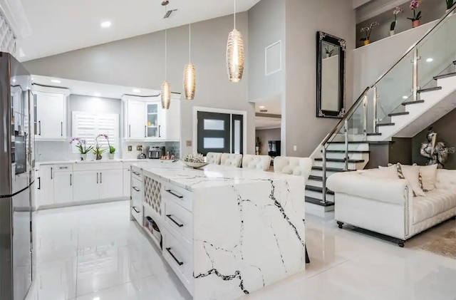 kitchen featuring decorative light fixtures, white cabinetry, light tile patterned floors, and high vaulted ceiling