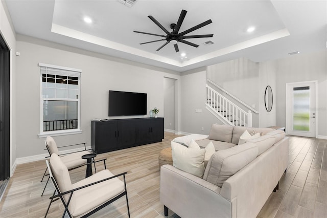 living room featuring a tray ceiling and light wood-type flooring