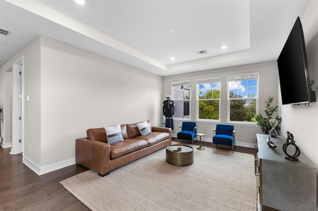 living room with dark hardwood / wood-style flooring and a raised ceiling