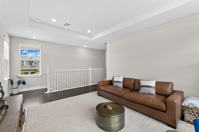 living room with hardwood / wood-style floors and a tray ceiling