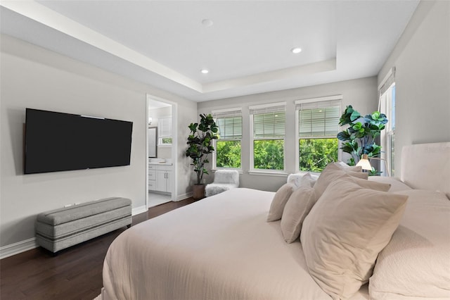 bedroom featuring a tray ceiling, dark hardwood / wood-style flooring, and multiple windows