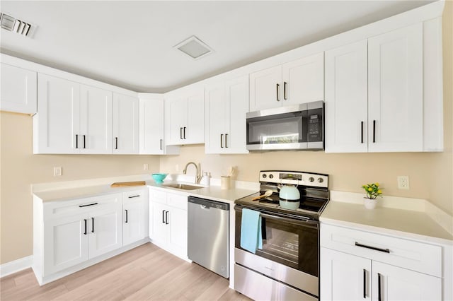 kitchen with stainless steel appliances, light countertops, a sink, and white cabinetry