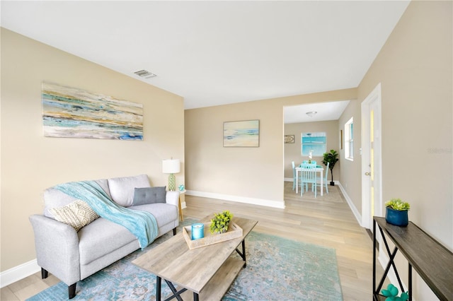 living area with light wood-style floors, baseboards, and visible vents