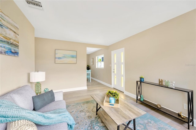 living area with visible vents, baseboards, and wood finished floors