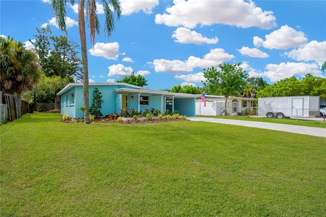 view of front facade with covered porch, a front yard, fence, an attached carport, and driveway