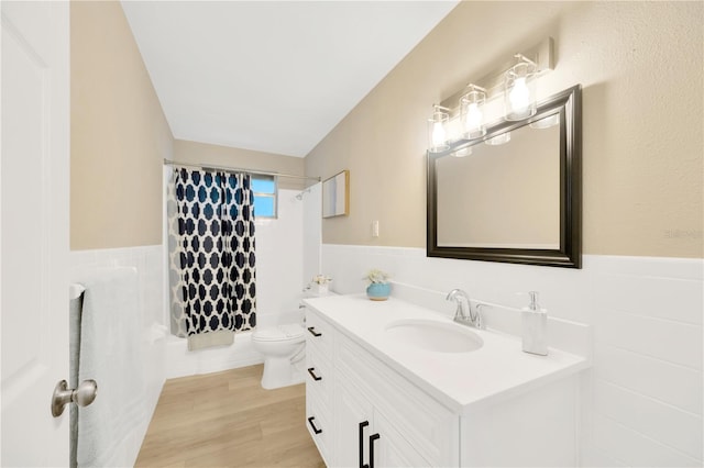 full bathroom with a wainscoted wall, tile walls, toilet, vanity, and wood finished floors