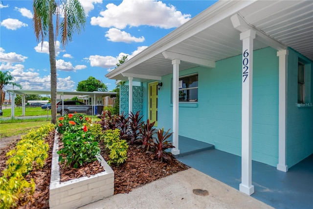 entrance to property with a carport, concrete block siding, and covered porch