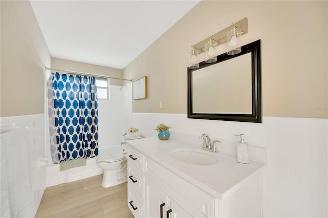 full bath featuring curtained shower, toilet, a wainscoted wall, vanity, and tile walls