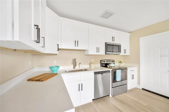 kitchen featuring light countertops, appliances with stainless steel finishes, a sink, and white cabinets